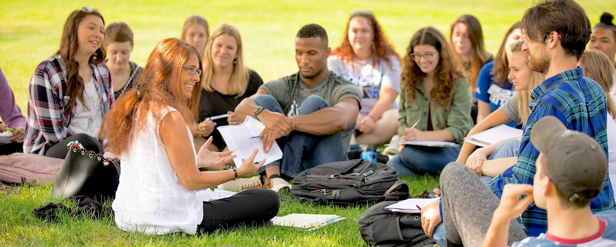 students sitting outside with professor